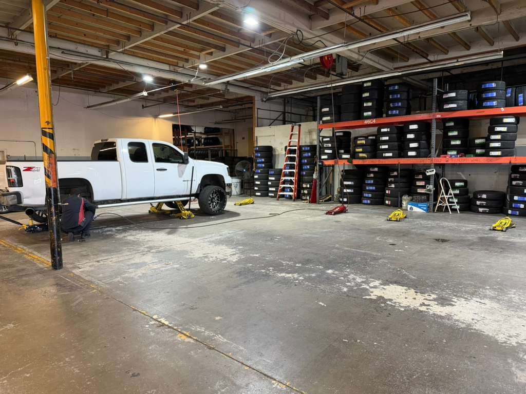 Lifted GMC truck up on jack stands beside tire racks